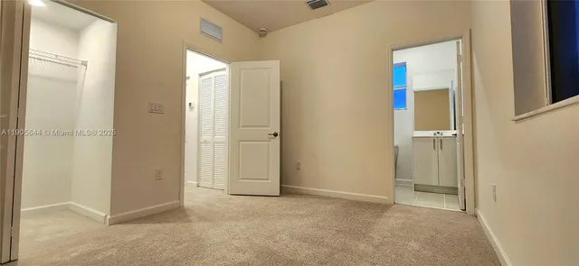 a view of an empty room with closet and a window