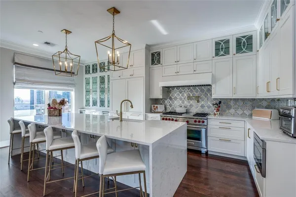 a kitchen with stainless steel appliances granite countertop a stove top oven a sink a dining table and chairs with wooden floor