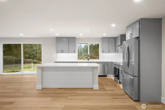 a kitchen with kitchen island a sink cabinets and stainless steel appliances