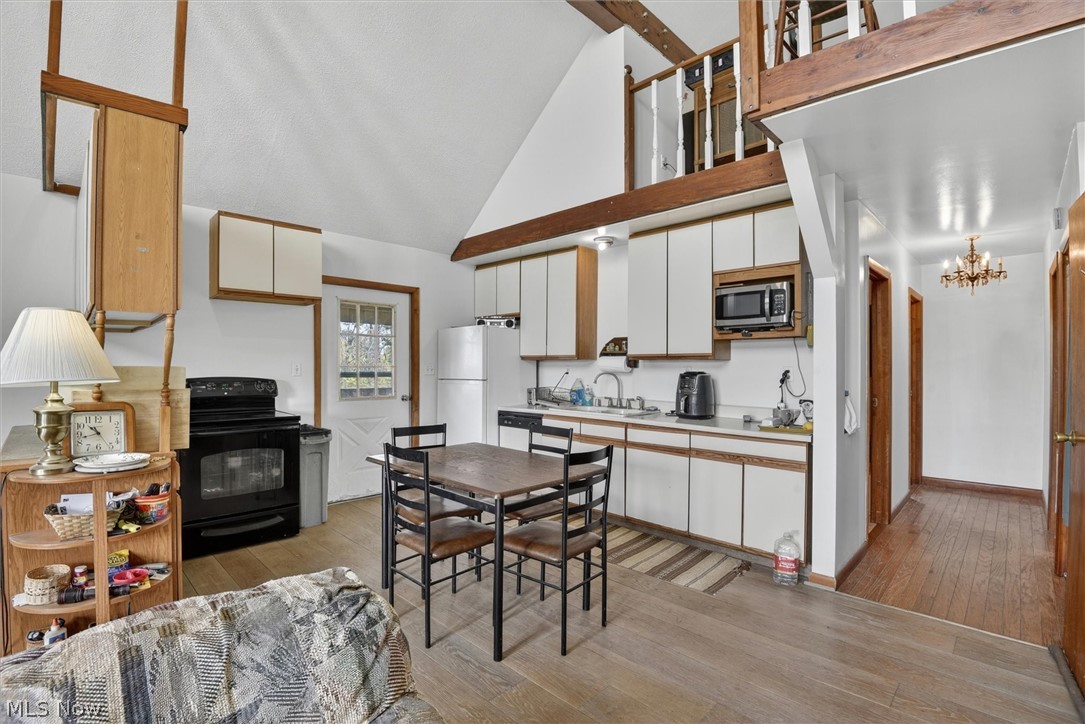 1526 Stevenson Road Ashtabula, OH 44004 - Photo 16 of 50 Open-concept kitchen area featuring a vaulted ceiling with exposed wood beams, white cabinetry, and wood-finish flooring