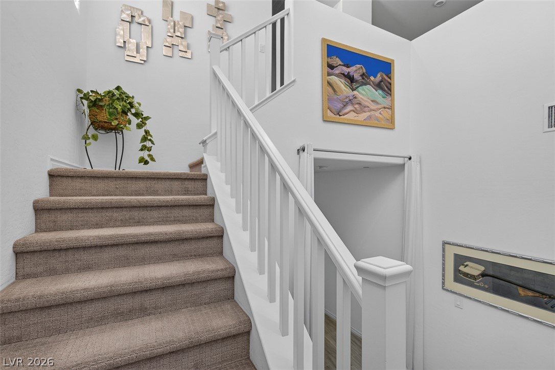 1824 Redland Ridge Street Henderson, NV 89002 - Photo 29 of 69 Carpeted staircase with white railings ascends to an upper level, showcasing clean lines and inviting transitions.