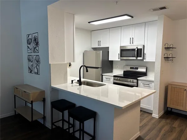 a kitchen with stainless steel appliances a microwave sink refrigerator and cabinets