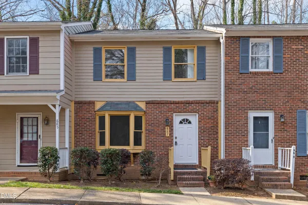 front view of a brick house with a yard and large tree