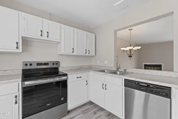 a kitchen with granite countertop white cabinets and stainless steel appliances