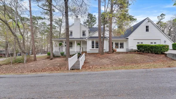 a front view of a house with a yard and large trees