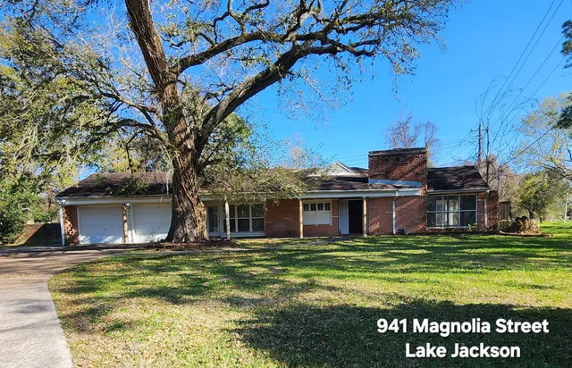 a view of a house with a big yard and large trees