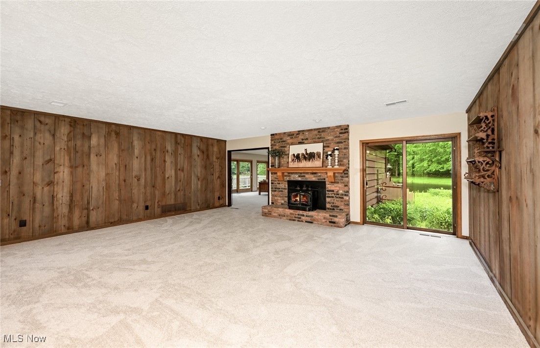 4010 State Road Medina, OH 44256 - Photo 8 of 50 Unfurnished living room featuring wood walls, a textured ceiling, light carpet, plenty of natural light, and a fireplace