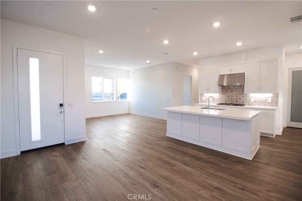 635 Gadwall Irvine, CA 92618 - Photo 2 of 27 a large kitchen with kitchen island a sink dishwasher a refrigerator and white cabinets with wooden floor