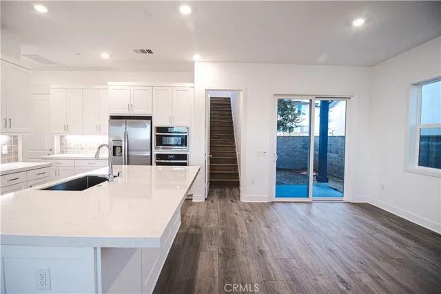 an open kitchen with wooden floor and refrigerator