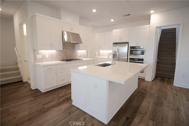 a kitchen that has a lot of cabinets a sink and wooden floor