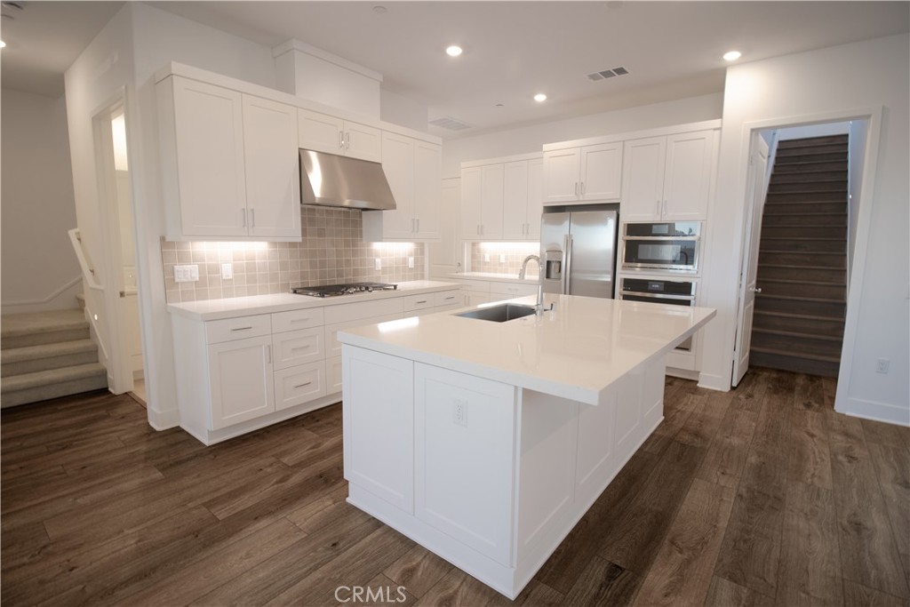 635 Gadwall Irvine, CA 92618 - Photo 4 of 27 a kitchen that has a lot of cabinets a sink and wooden floor