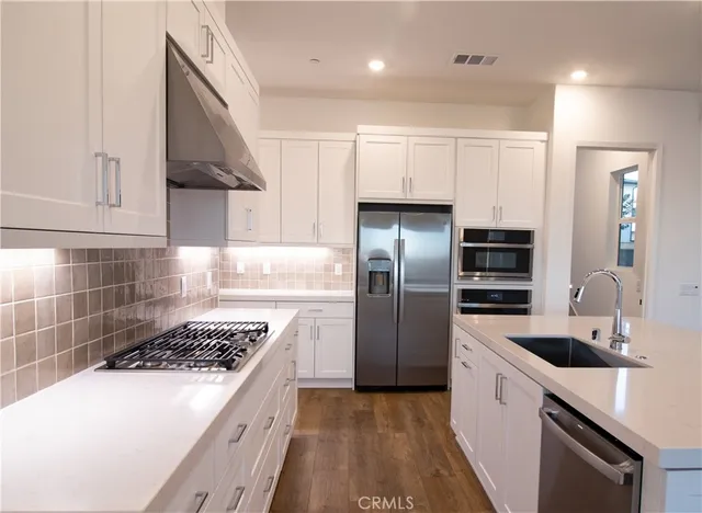 a kitchen with stainless steel appliances a sink a stove a refrigerator and cabinets