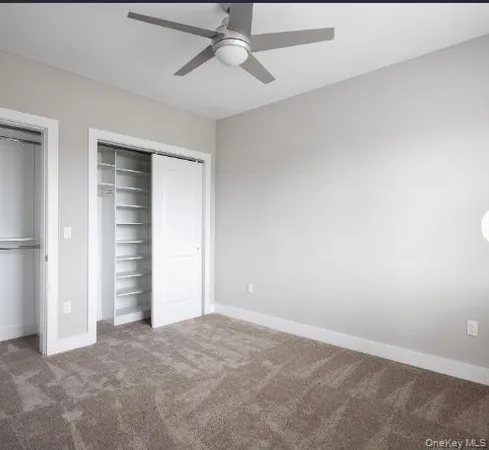 an empty room with closet and a ceiling fan