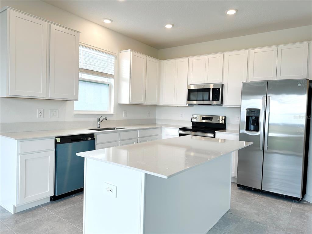 700 Daring Drive Davenport, FL 33837 - Photo 7 of 22 a kitchen with a sink a microwave a refrigerator and cabinets