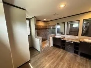 a spacious bathroom with a double vanity sink a mirror and a shower