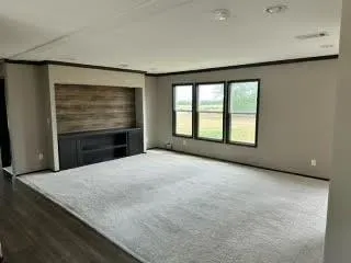 a view of an empty room with a window and a kitchen