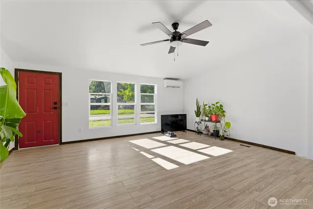 a view of an empty room with a window and wooden floor