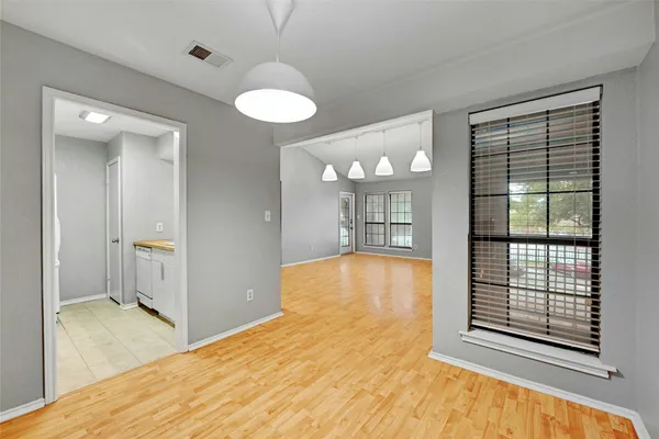 a view of an empty room with a window and wooden floor