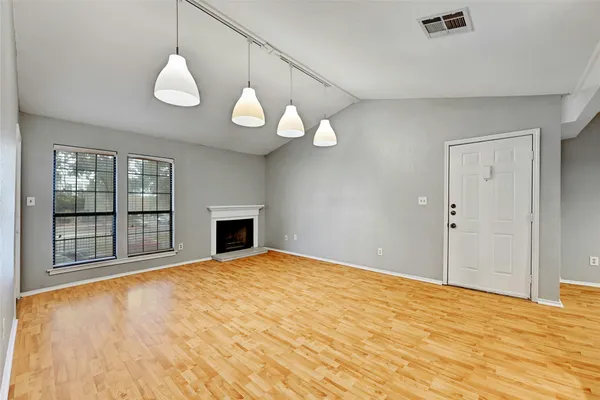 a view of an empty room with a window and wooden floor