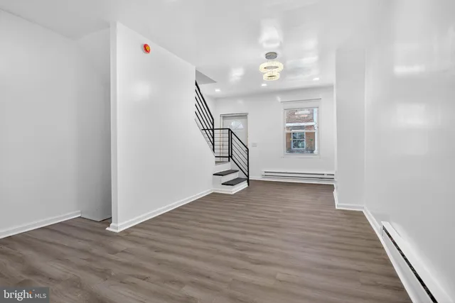 a view of an empty room with wooden floor and stairs
