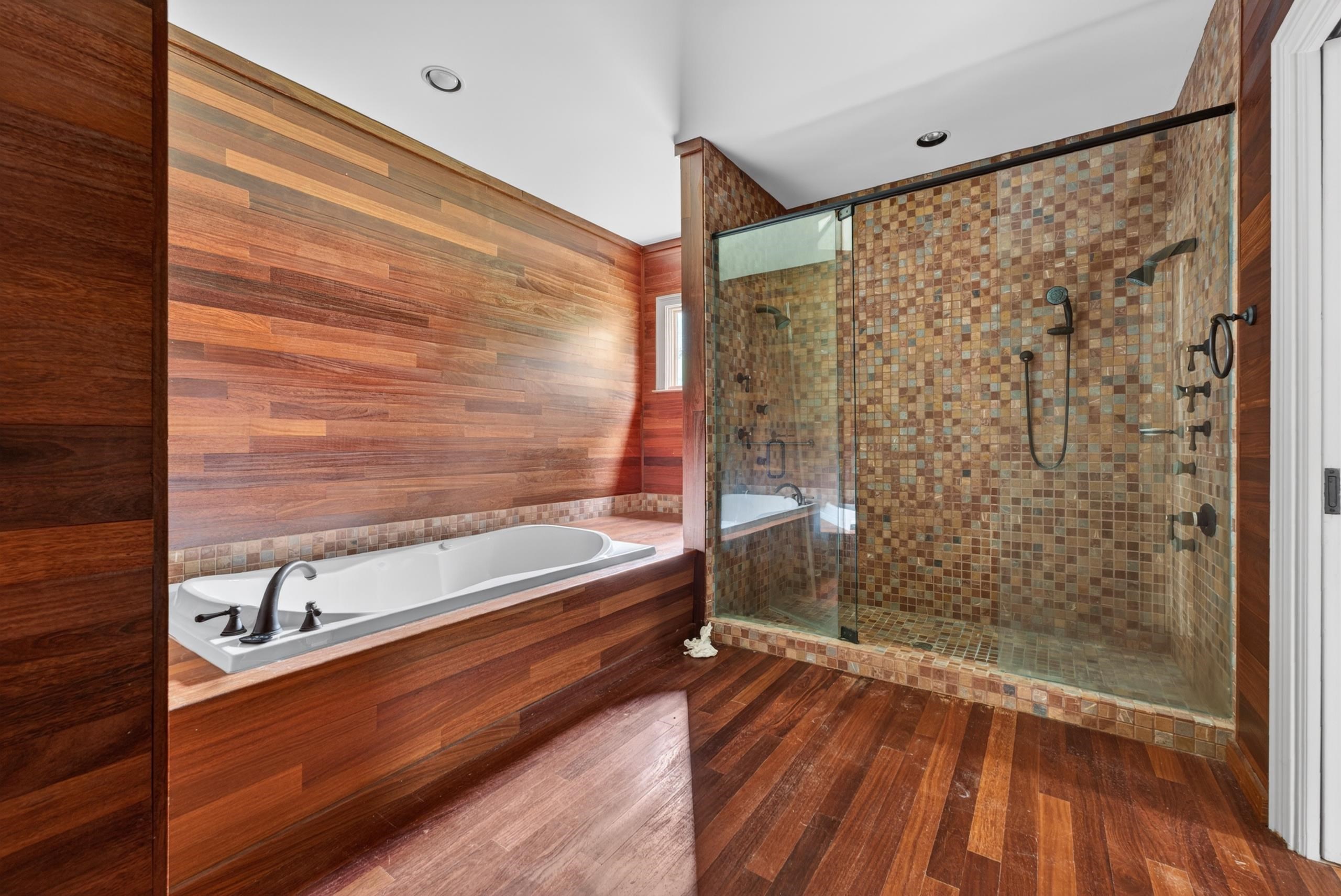 530 West Raines Road Memphis, TN 38109 - Photo 37 of 38 Bathroom featuring wood-finish wall paneling, a built-in soaking tub with dark-finish fixtures, and a glass-enclosed shower with mosaic tile surround