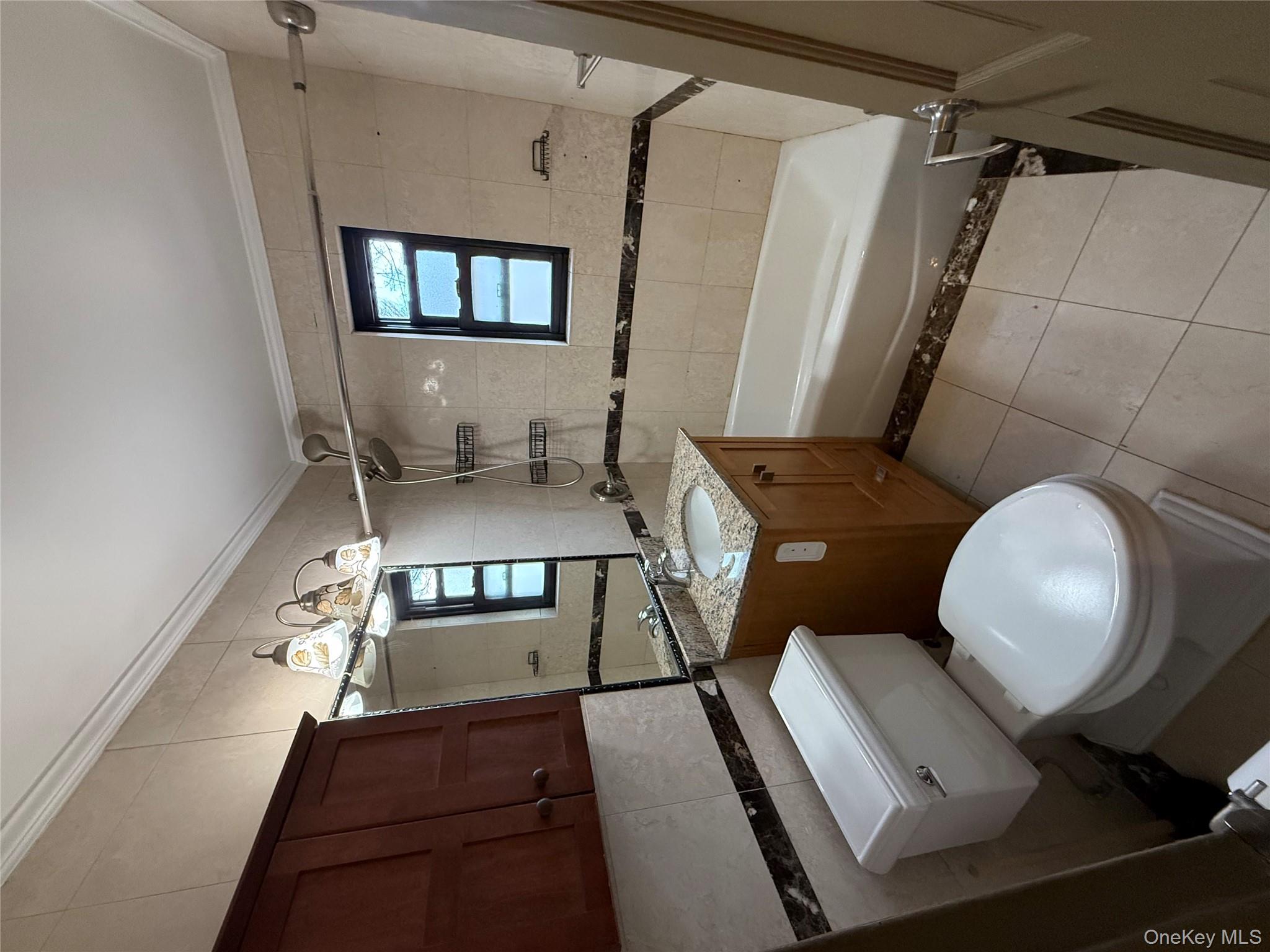 a bathroom with a granite countertop toilet sink and mirror