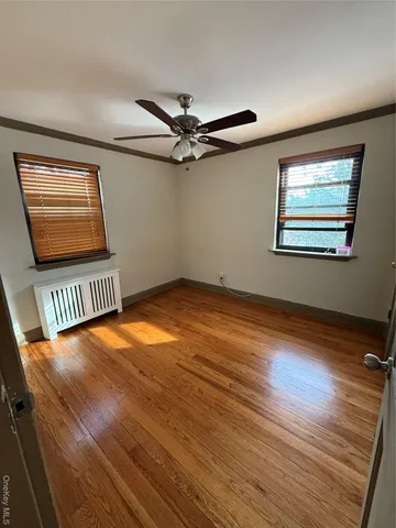 an empty room with wooden floor fan and windows