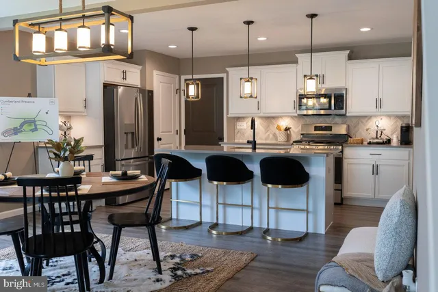 a kitchen with stainless steel appliances kitchen island granite countertop a dining table chairs and white cabinets