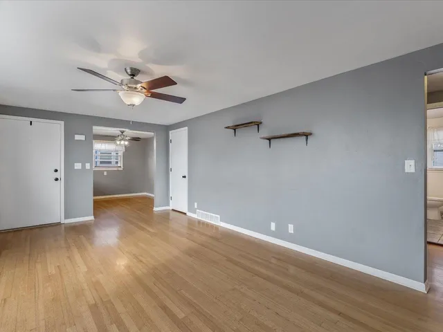 a view of an empty room with window and wooden floor