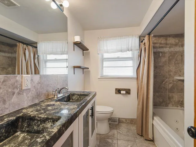 a bathroom with a granite countertop sink toilet and shower