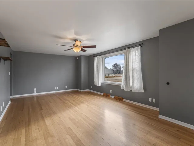 a view of an empty room with a window and wooden floor