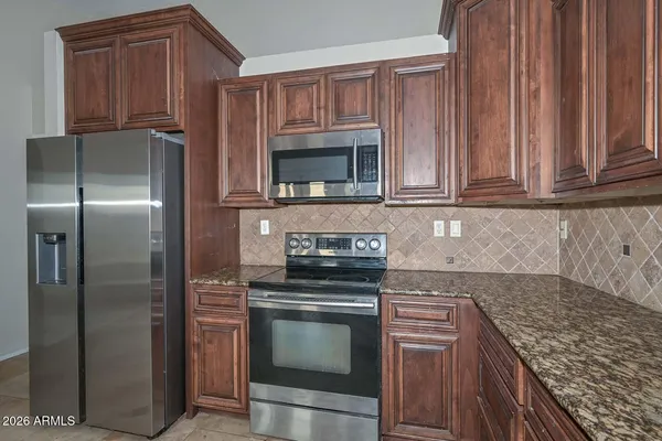 a kitchen with granite countertop a stove top oven microwave and cabinets