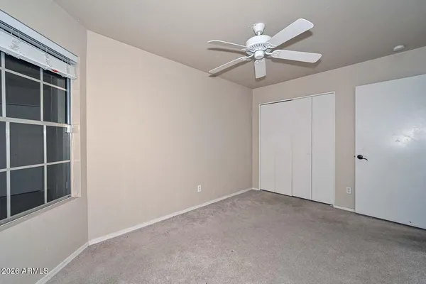 an empty room with a chandelier fan and windows