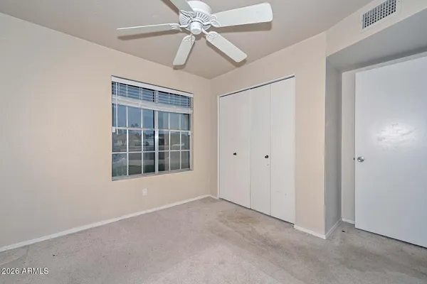 an empty room with windows and fan