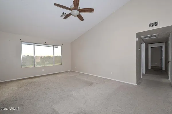 a view of empty room with wooden floor and fan