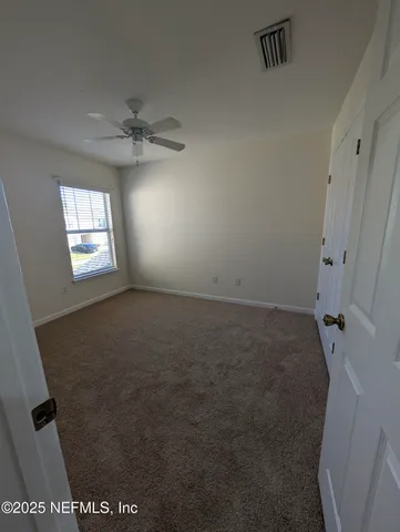 an empty room with windows and fan