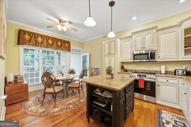 a open kitchen with stainless steel appliances granite countertop a stove top oven a dining table and chairs with wooden floor