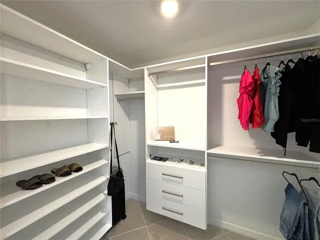 a view of walk in closet with clothes and shoes
