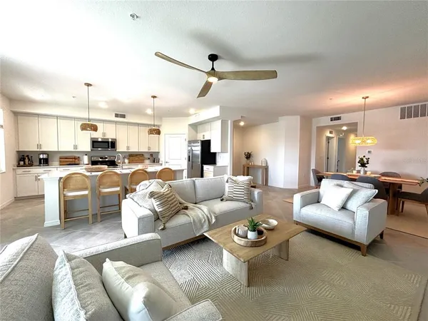 a living room with furniture kitchen view and a chandelier
