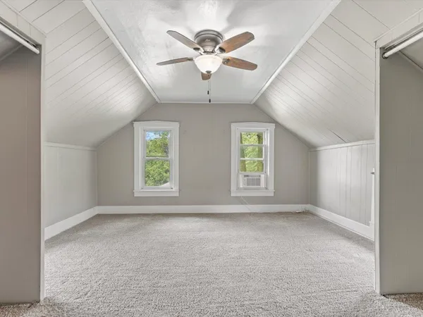 an empty room with ceiling fan and windows