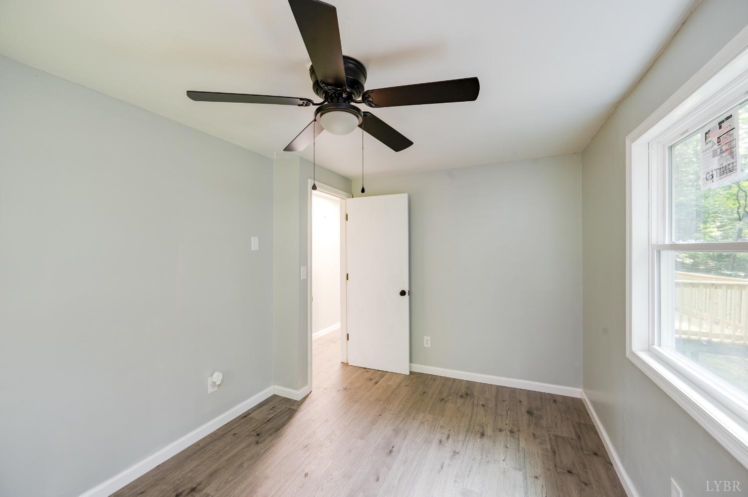 577 Thomas Road Madison Heights, VA 24572 - Photo 21 of 40 an empty room with wooden floor fan and windows