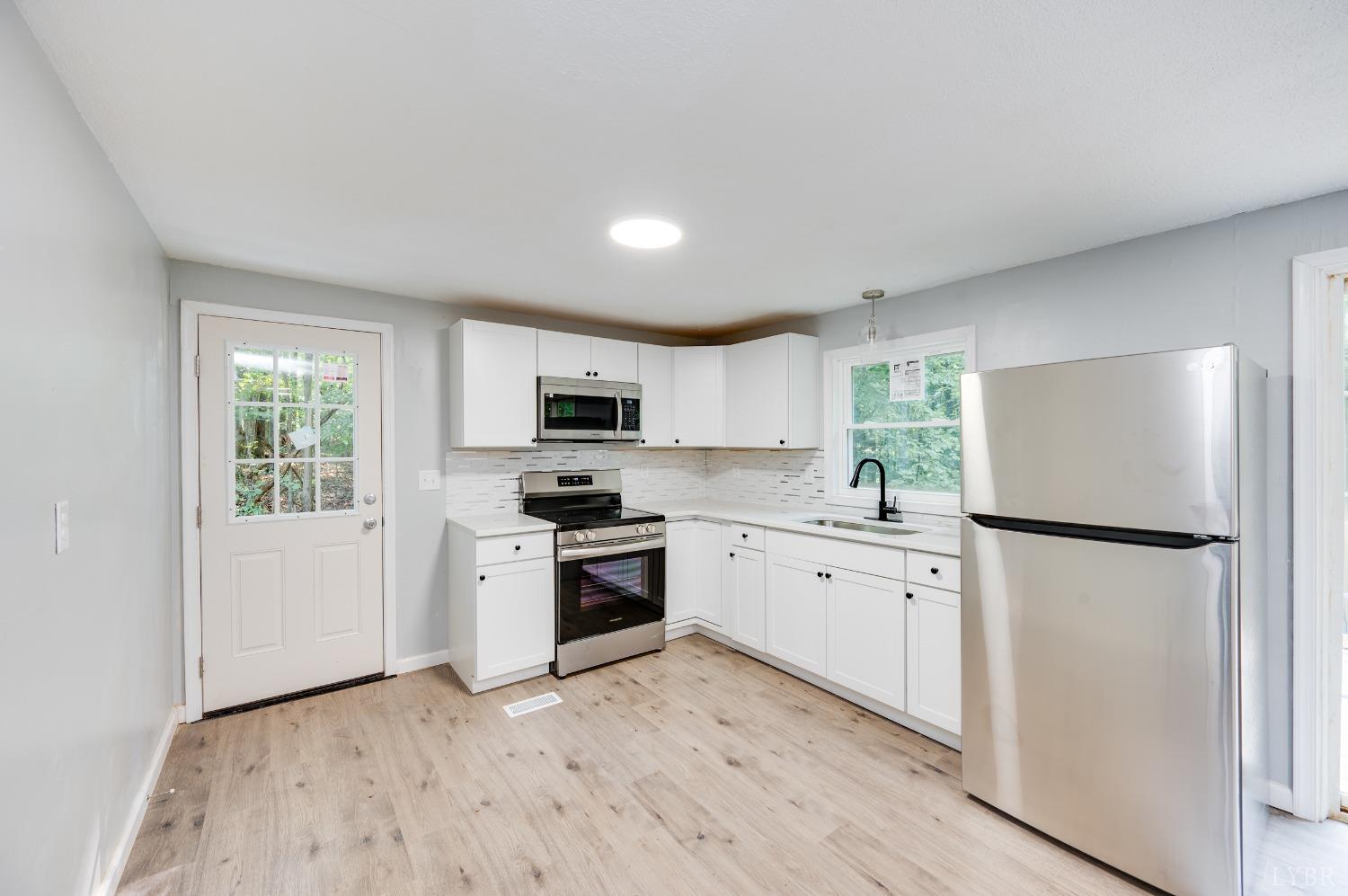 577 Thomas Road Madison Heights, VA 24572 - Photo 5 of 40 a kitchen with white cabinets and white appliances