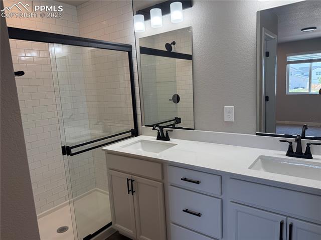 435 Atchison Way Calhan, CO 80808 - Photo 2 of 8 Bathroom featuring a textured wall, a shower stall, and double vanity