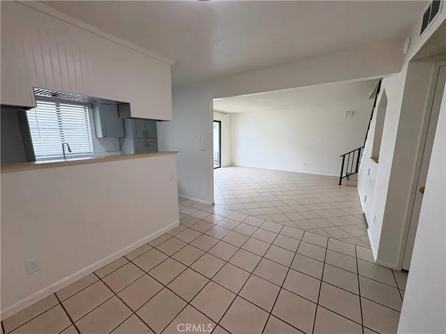 a view of a refrigerator in kitchen and an empty room