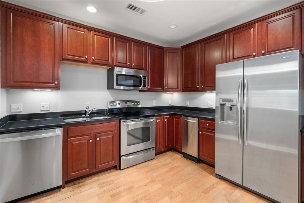 204 Clocktower Drive, Unit 206 Waltham, MA 02452 - Photo 13 of 27 a kitchen with stainless steel appliances granite countertop a refrigerator stove top oven a sink and dishwasher