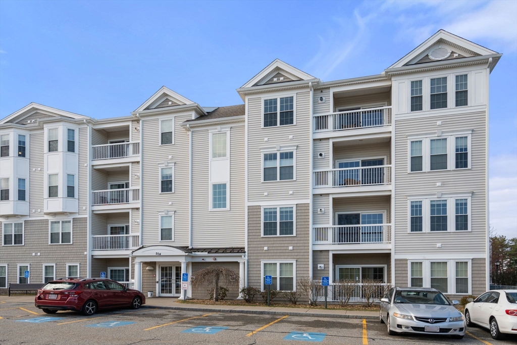204 Clocktower Drive, Unit 206 Waltham, MA 02452 - Photo 4 of 27 a front view of a building with lot of cars and trees