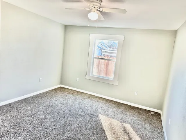 an empty room with a window and ceiling fan