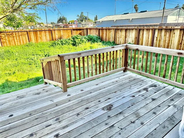 a view of a house with a deck and a yard with wooden fence