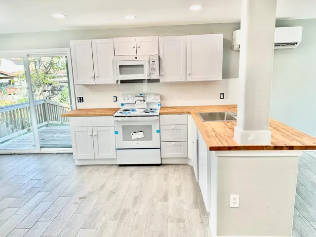 a kitchen with stainless steel appliances granite countertop a stove a sink and white cabinets with wooden floor