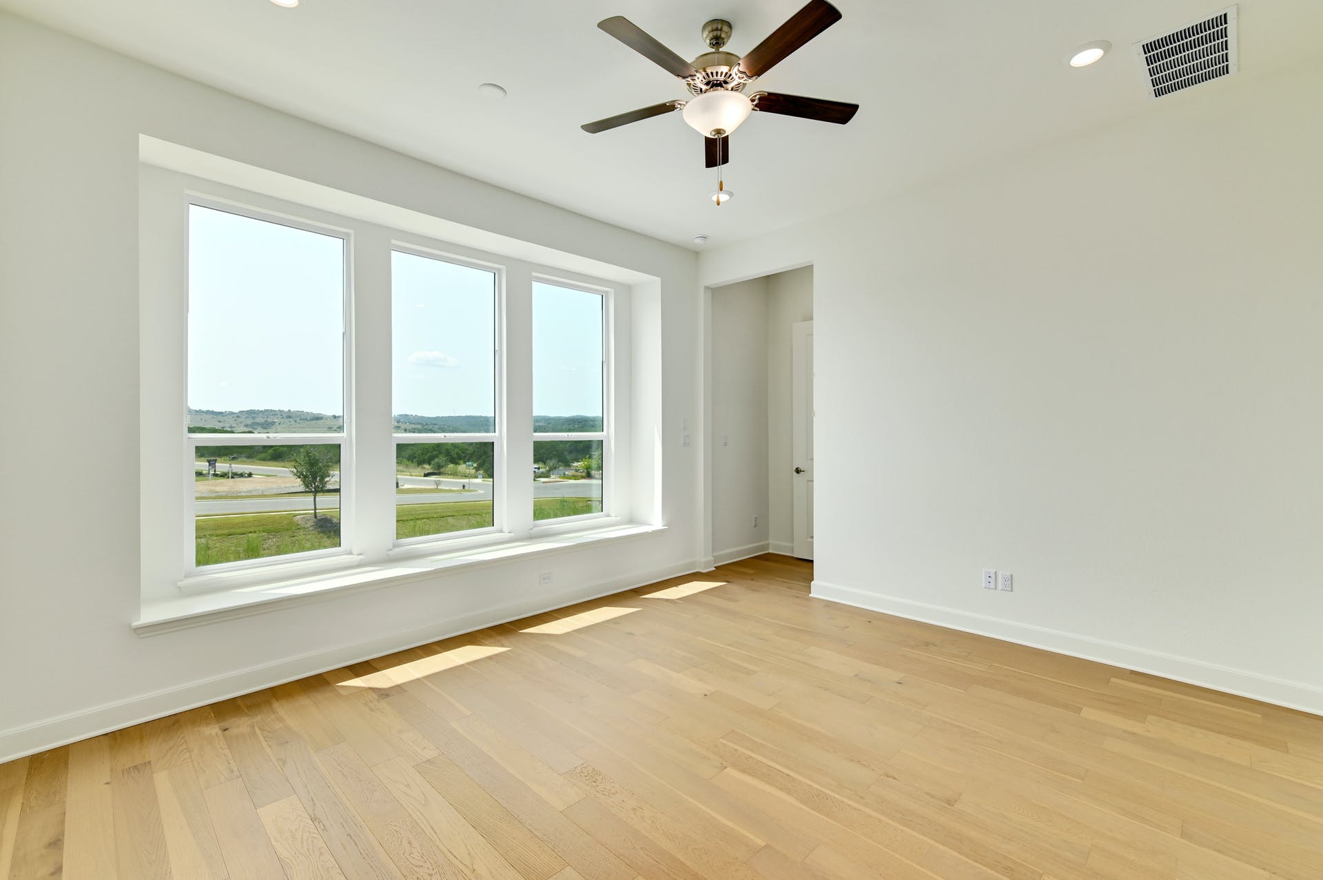 19005 Fernando Trail Austin, TX 78738 - Photo 17 of 35 Primary bedroom on main floor featuring large windows with unblocking view, high ceiling, bright, ceiling fan, light wood finished floors, and recessed lighting